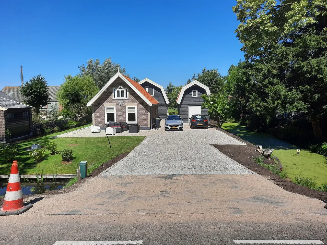 Zicht vanaf de weg op het erf met het woonhuis en de zwarte zomerhuizen