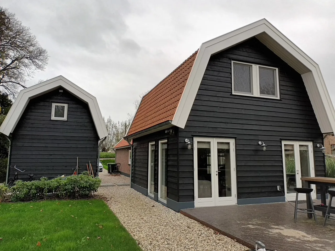 Twee zomerhuizen met zwarte gevels en wit afgewerkte dakranden