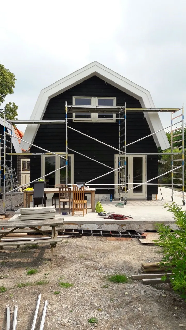 Gevelafwerking van het zomerhuis met steiger en bouwmaterialen